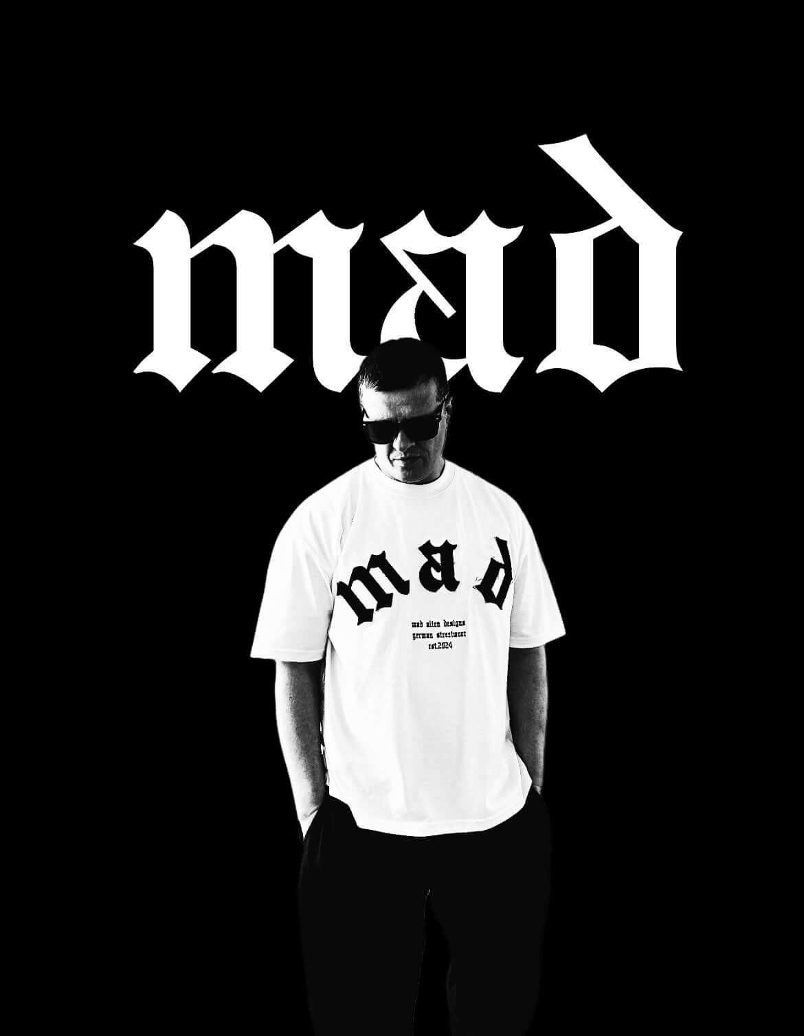 MAD T-Shirt in white worn by a model against a black background, showcasing a modern streetwear style.